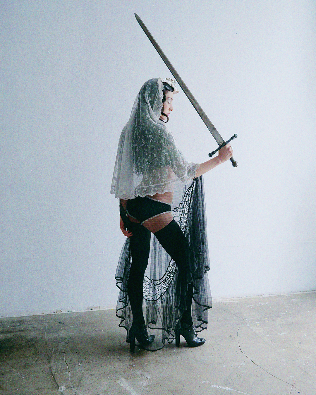 Holly Humberstone in veil dress standing with a sword